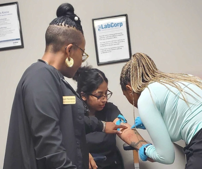 students training to take blood draws with their instructor nearby